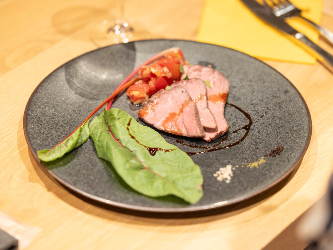 黒いプレートに盛り付けられたオーストラリア産牛肉の一皿。彩り野菜とソースが添えられている。