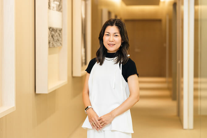 廊下でポーズをとる上田杏菜氏。上田杏菜インタビュー記事「アボリジナル・アートがもたらす、現代社会への眼差し」のサムネイル。