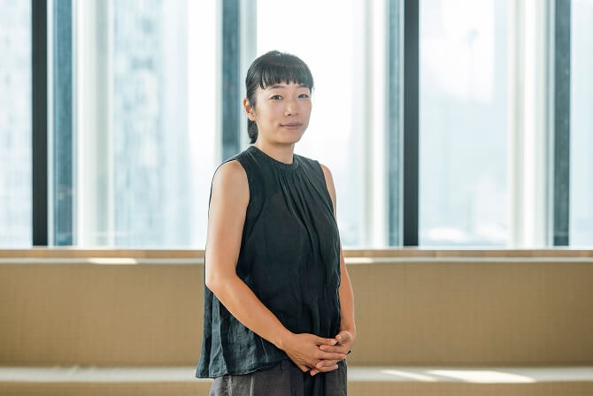 窓のある室内で、正面を向いて立つ中山晴奈氏。中山晴奈インタビュー記事「アートの解釈を促すフードデザインのアプローチ」のサムネイル。